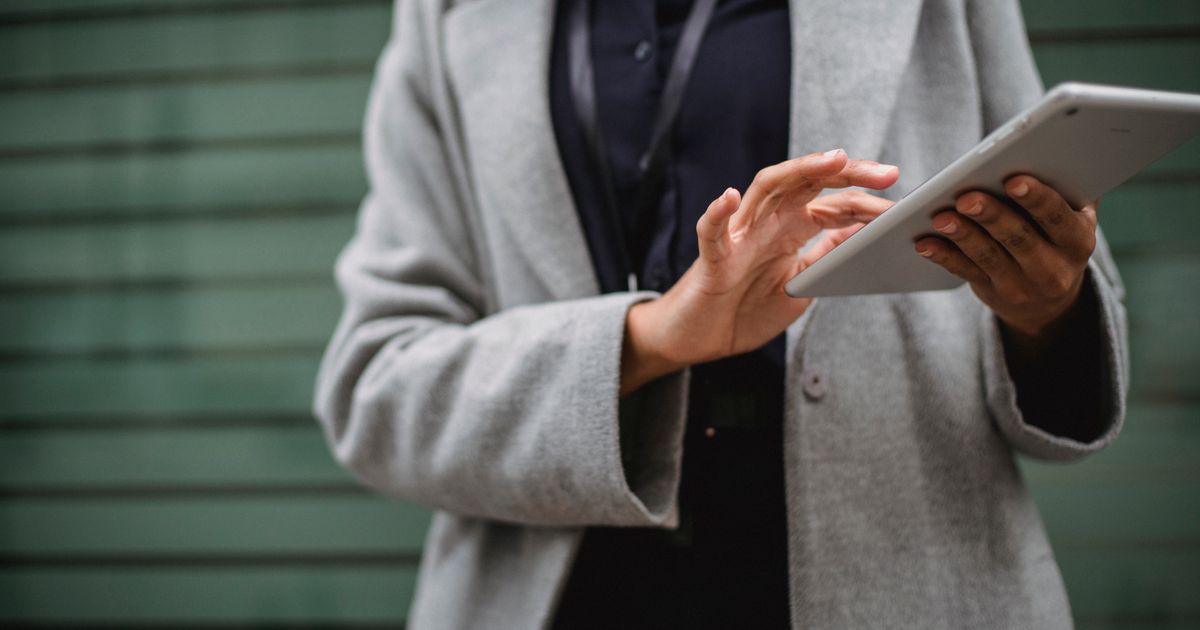 A professional in a grey coat using a tablet