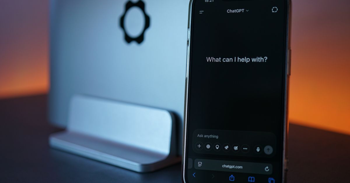 A smartphone showing a ChatGPT chat screen beside a laptop