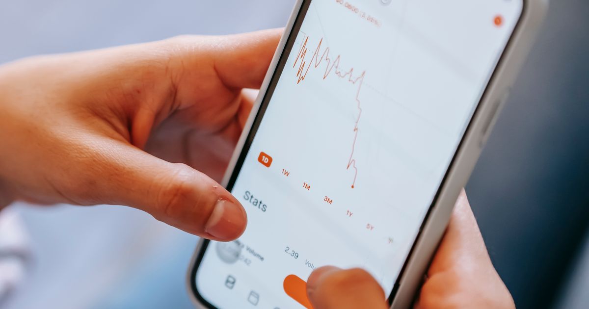 Hands holding a smartphone showing a finance app chart