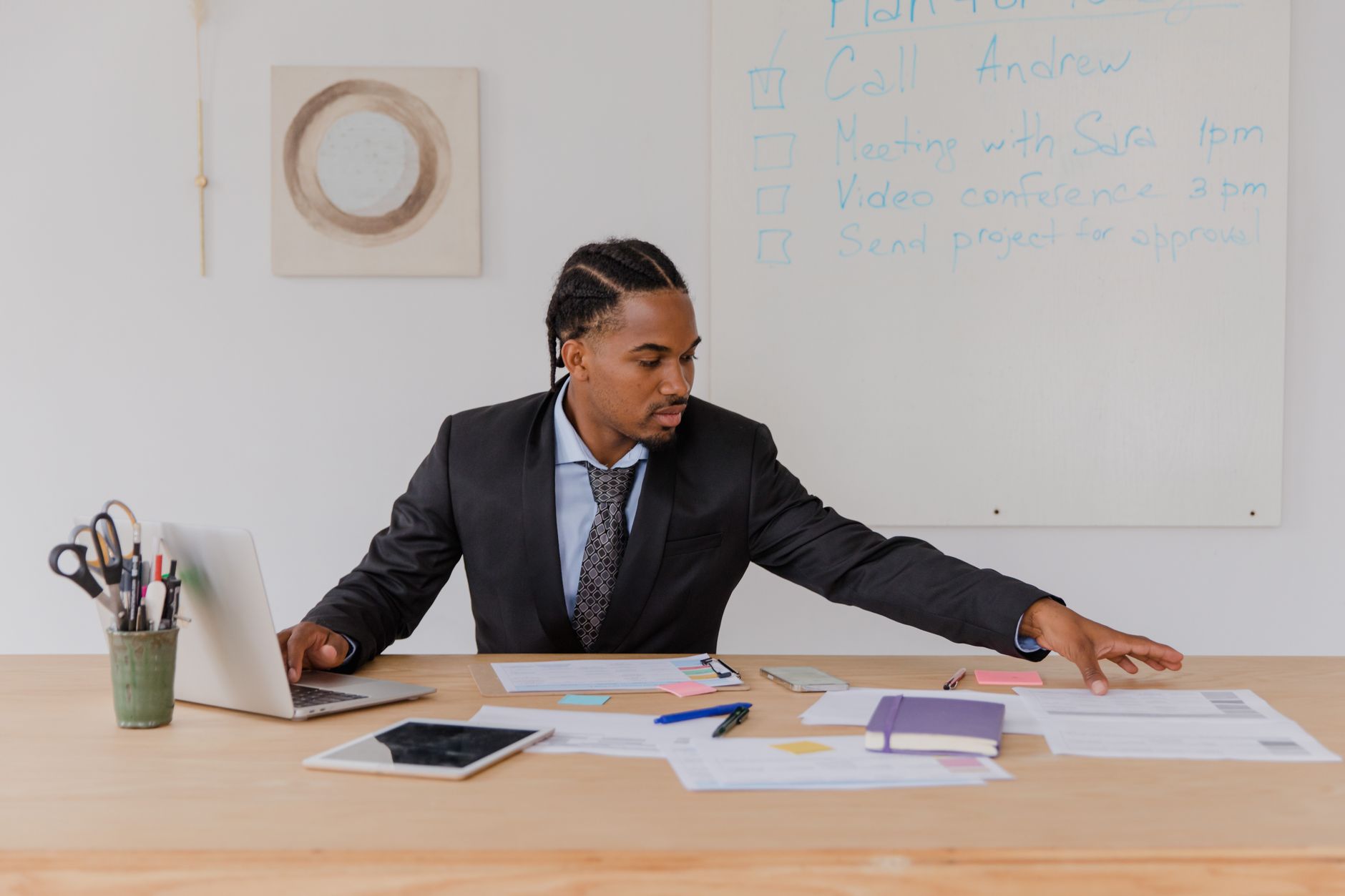 man sitting at his desk reaching for documents