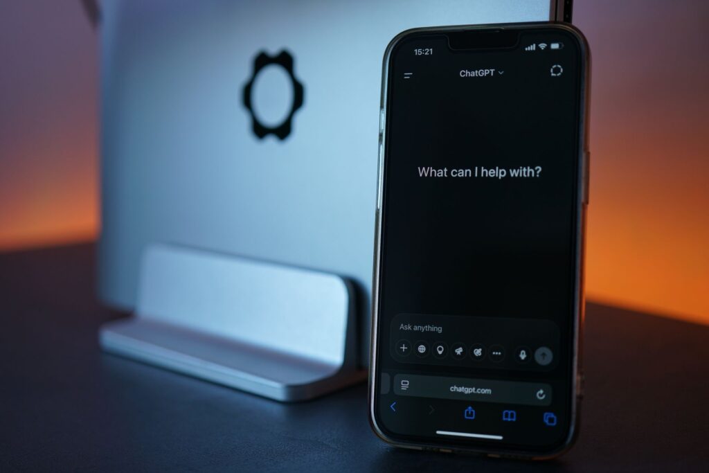 smartphone displaying chat interface with laptop