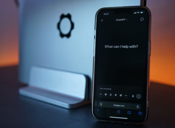 smartphone displaying chat interface with laptop